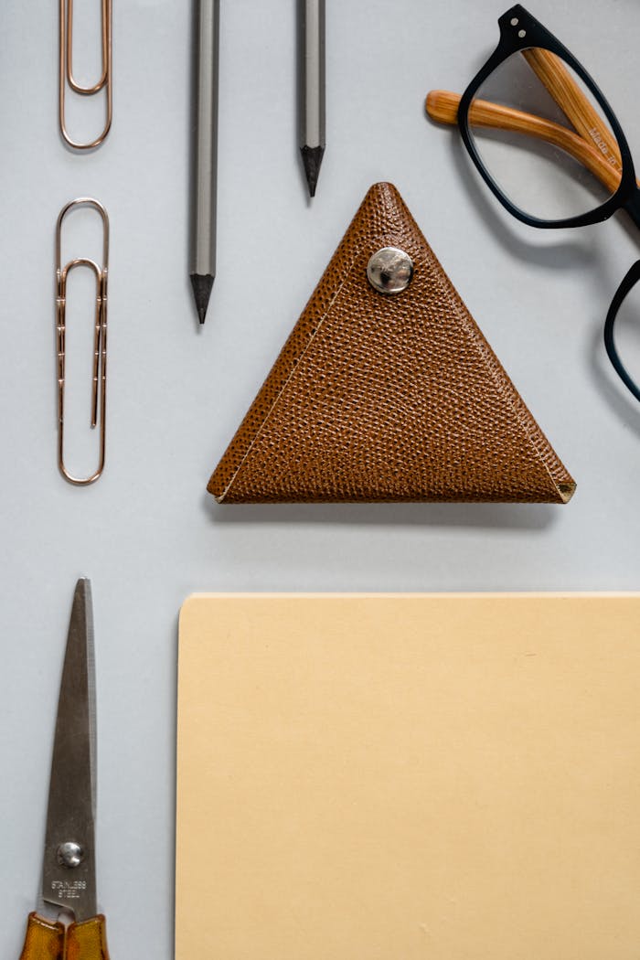 A top view flat lay of office essentials including a triangular case and glasses.